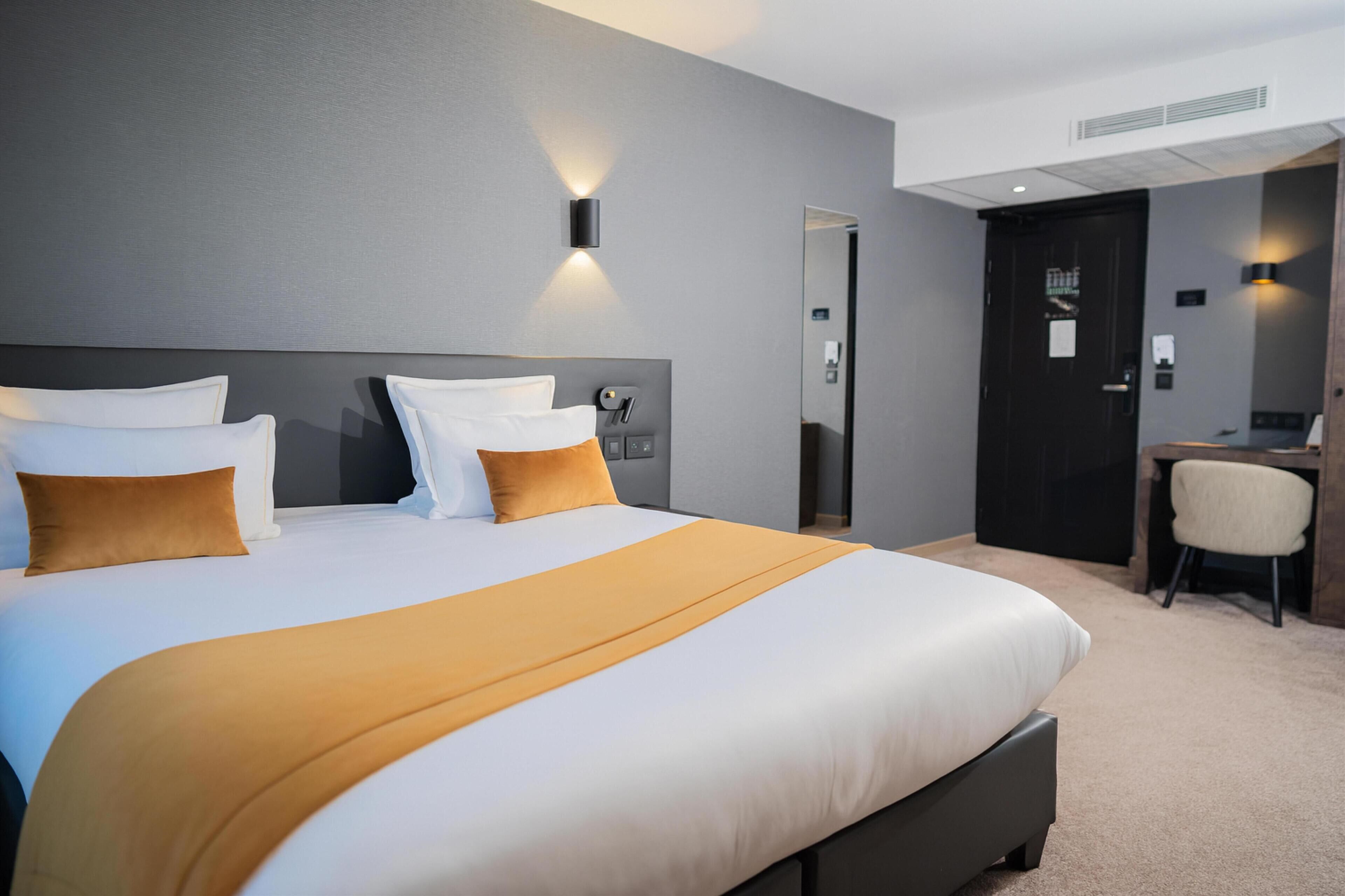 A hotel room with a large bed, a desk, and a chair.