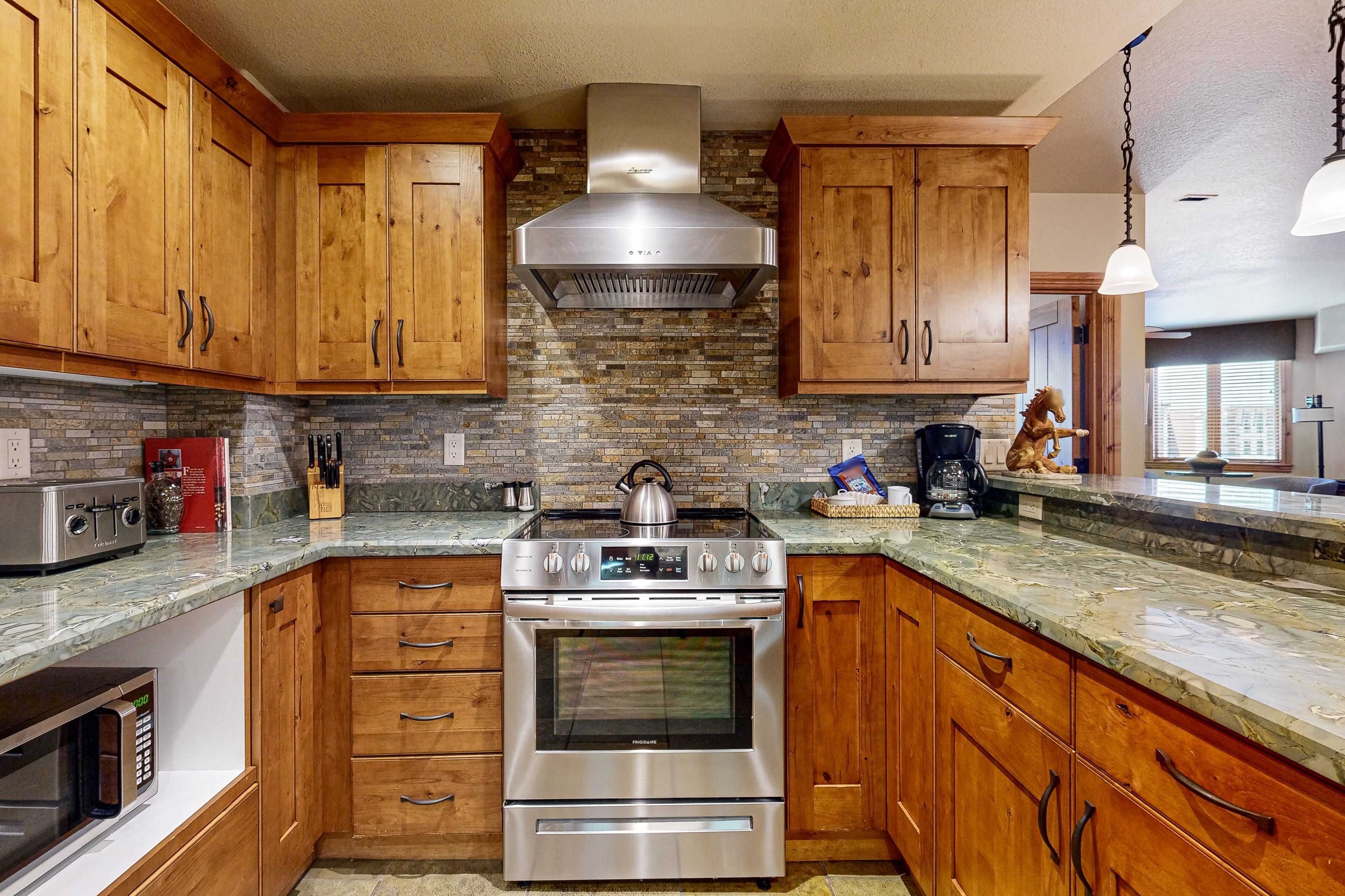 A kitchen with wooden cabinets, a stainless steel stove, and a brick backsplash.