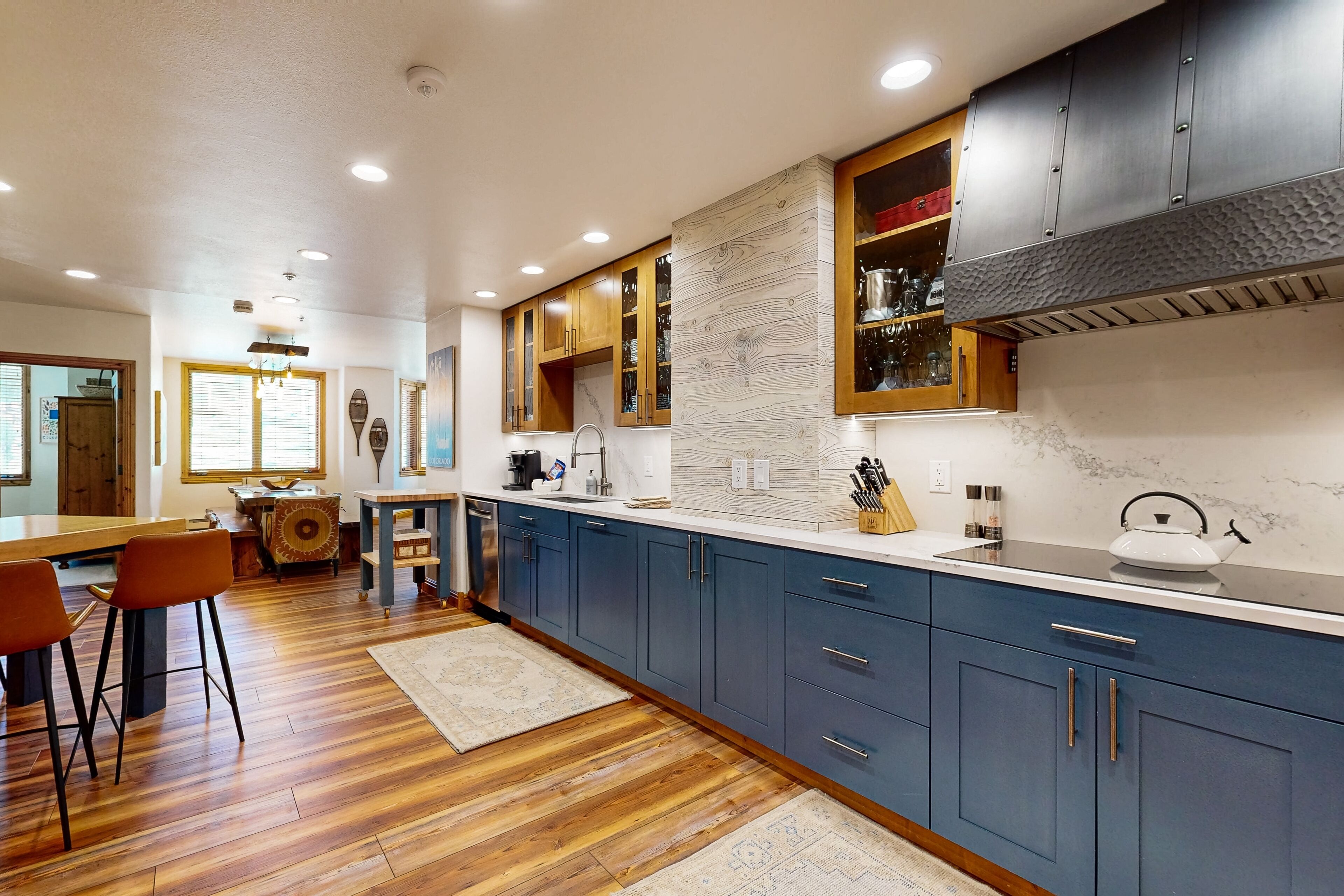 Una cocina moderna con armarios azules, suelo de madera y una isla central.