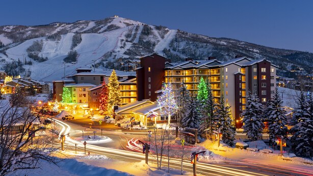 A hotel with multiple floors, a ski slope in the background, and a snow-covered landscape. - Torian Plum Condominiums (Steamboat Springs)