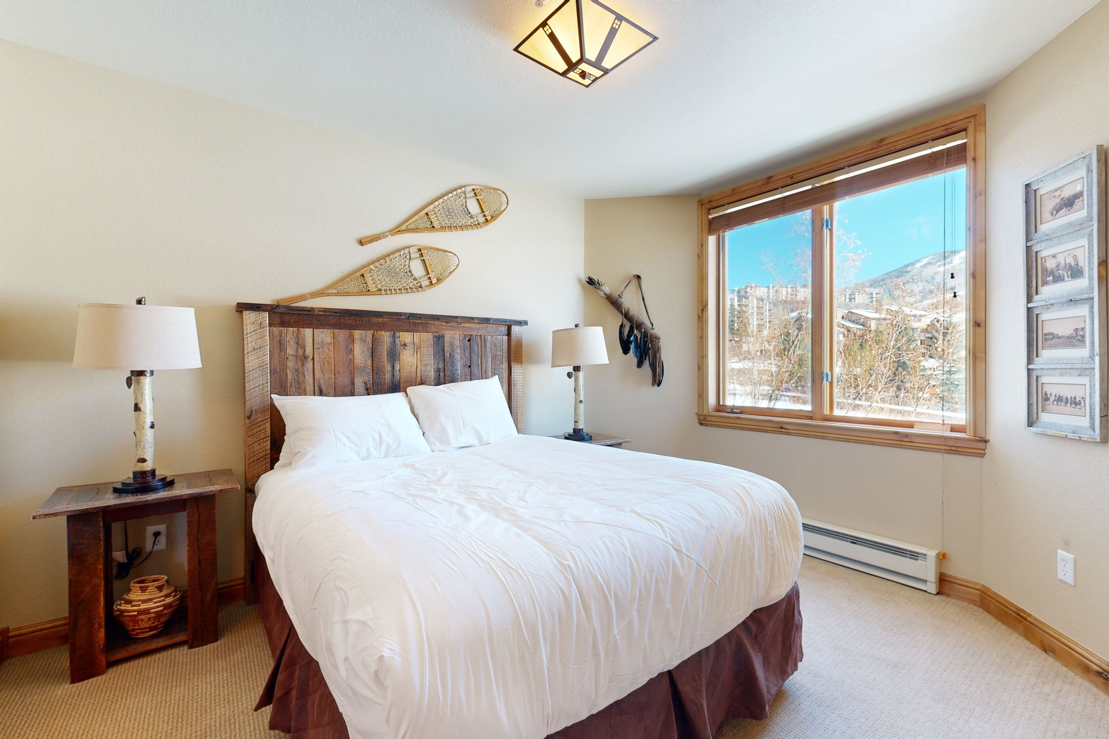 Une chambre dotée d’un grand lit, de deux tables de chevet avec des lampes, d’une fenêtre offrant une vue agréable et d’éléments décoratifs fixés au mur.