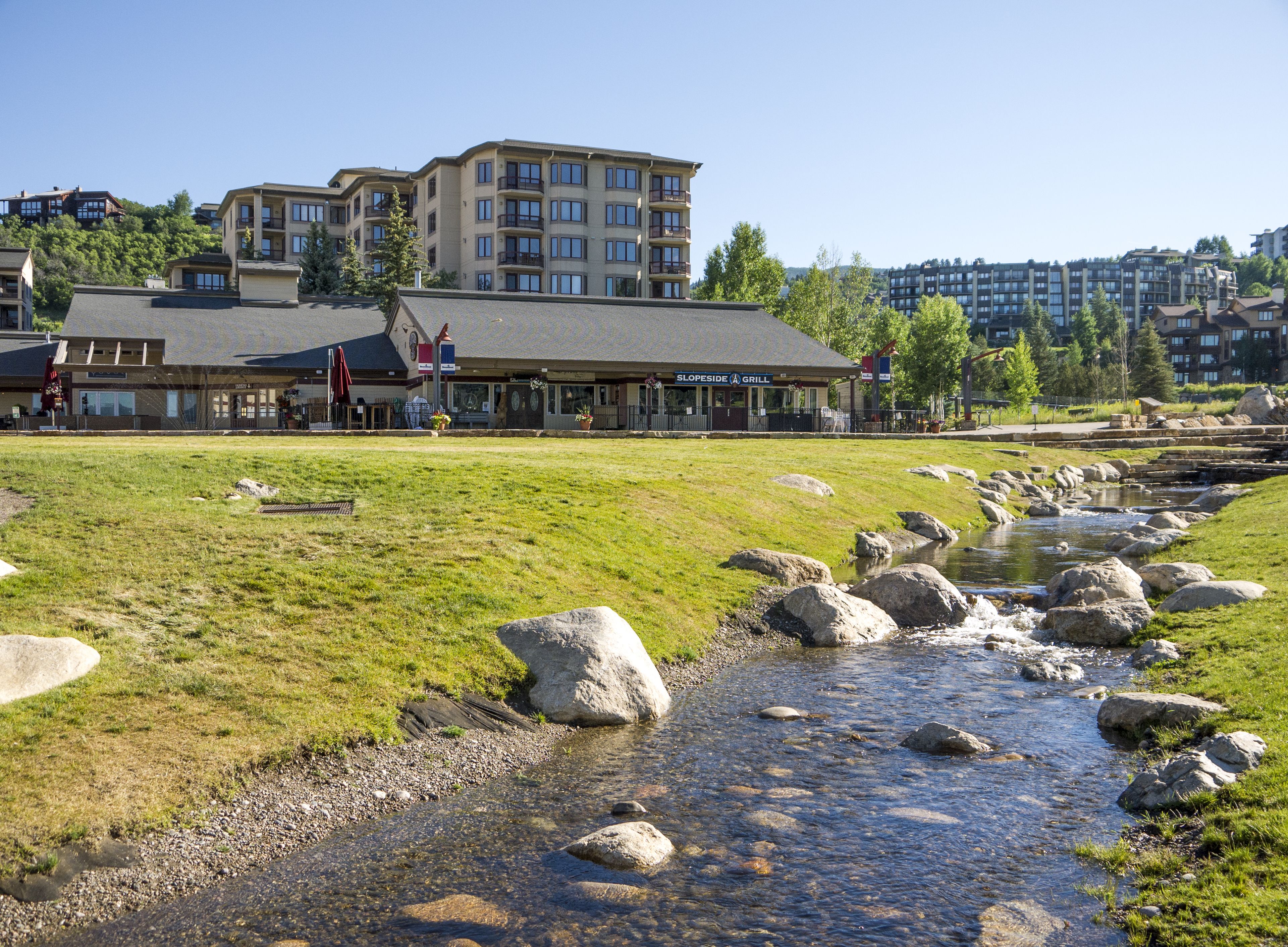 A riverside view with a restaurant and multi-story buildings in the background.
