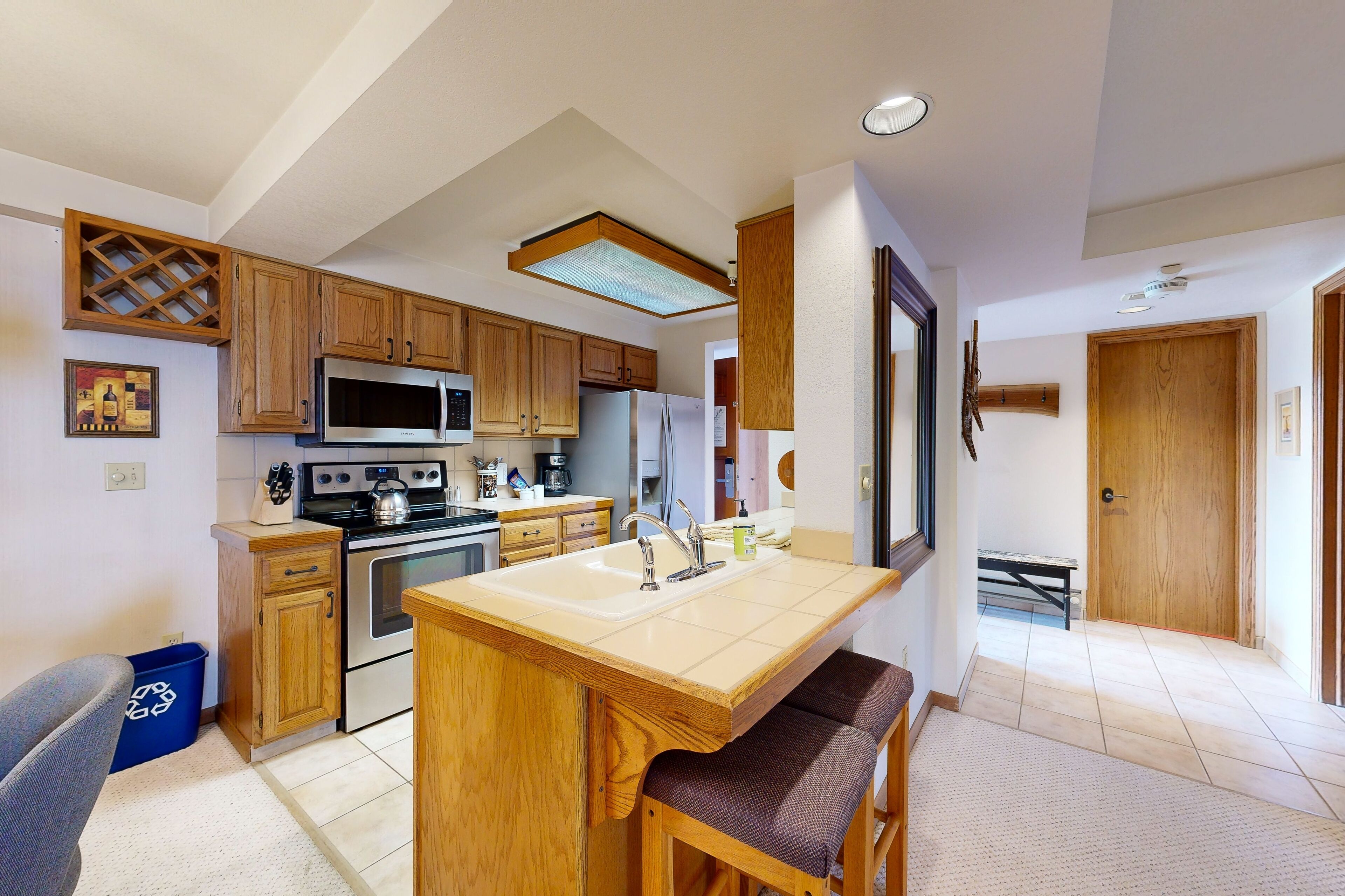 A modern kitchen with wooden cabinets, stainless steel appliances, and a central island with seating.