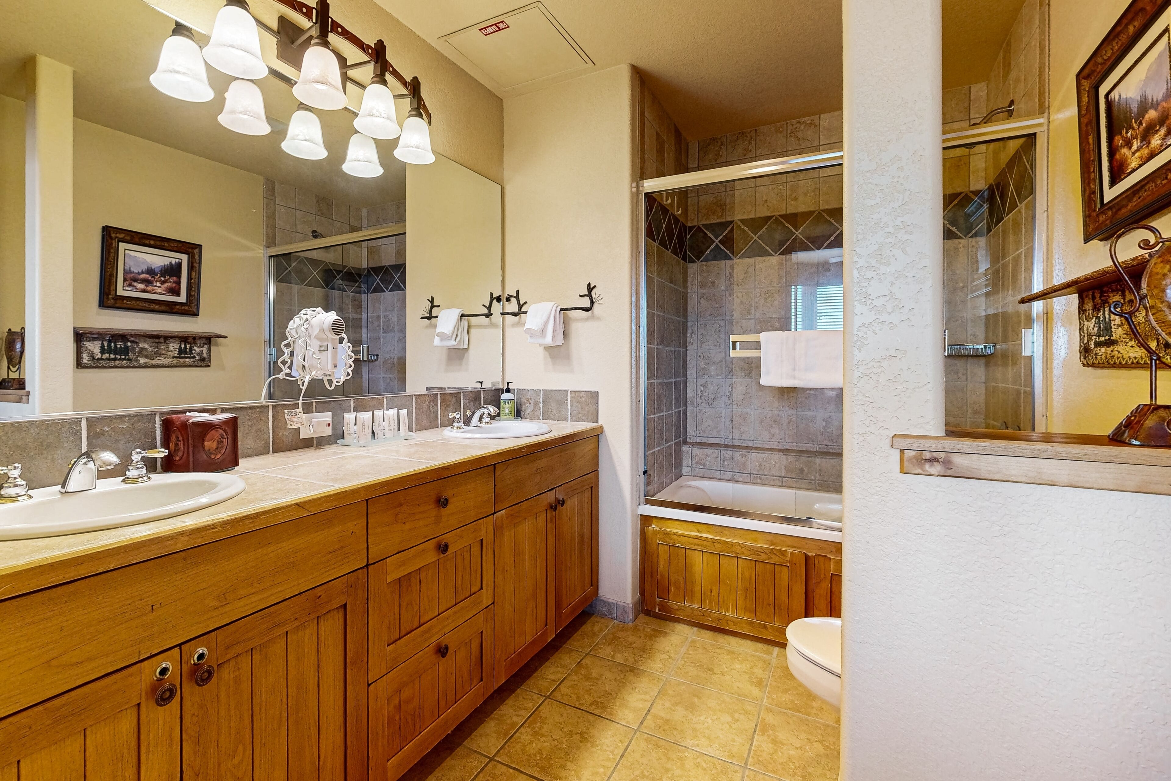 Een badkamer met een houten wastafelmeubel, een grote spiegel en een douchehoek.