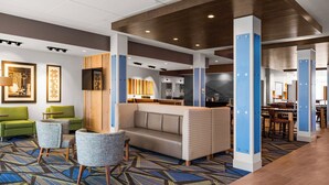 A hotel lobby with a modern design, featuring a seating area with sofas and armchairs, a patterned carpet, and wooden accents on the ceiling. - Holiday Inn Express & Suites Sanford- Lake Mary by IHG (Sanford)