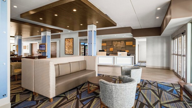 A modern lobby with a sofa, chairs, a reception desk, and a patterned carpet. - Holiday Inn Express & Suites Sanford- Lake Mary by IHG (Sanford)