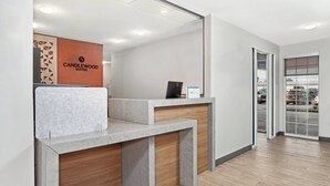 A reception desk with a wooden panel and a sign that reads "CANDLEWOOD SUITES".