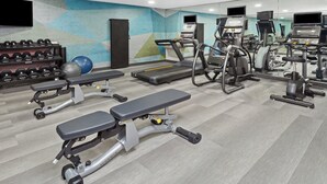 A gym with treadmills, elliptical machines, and weight benches.