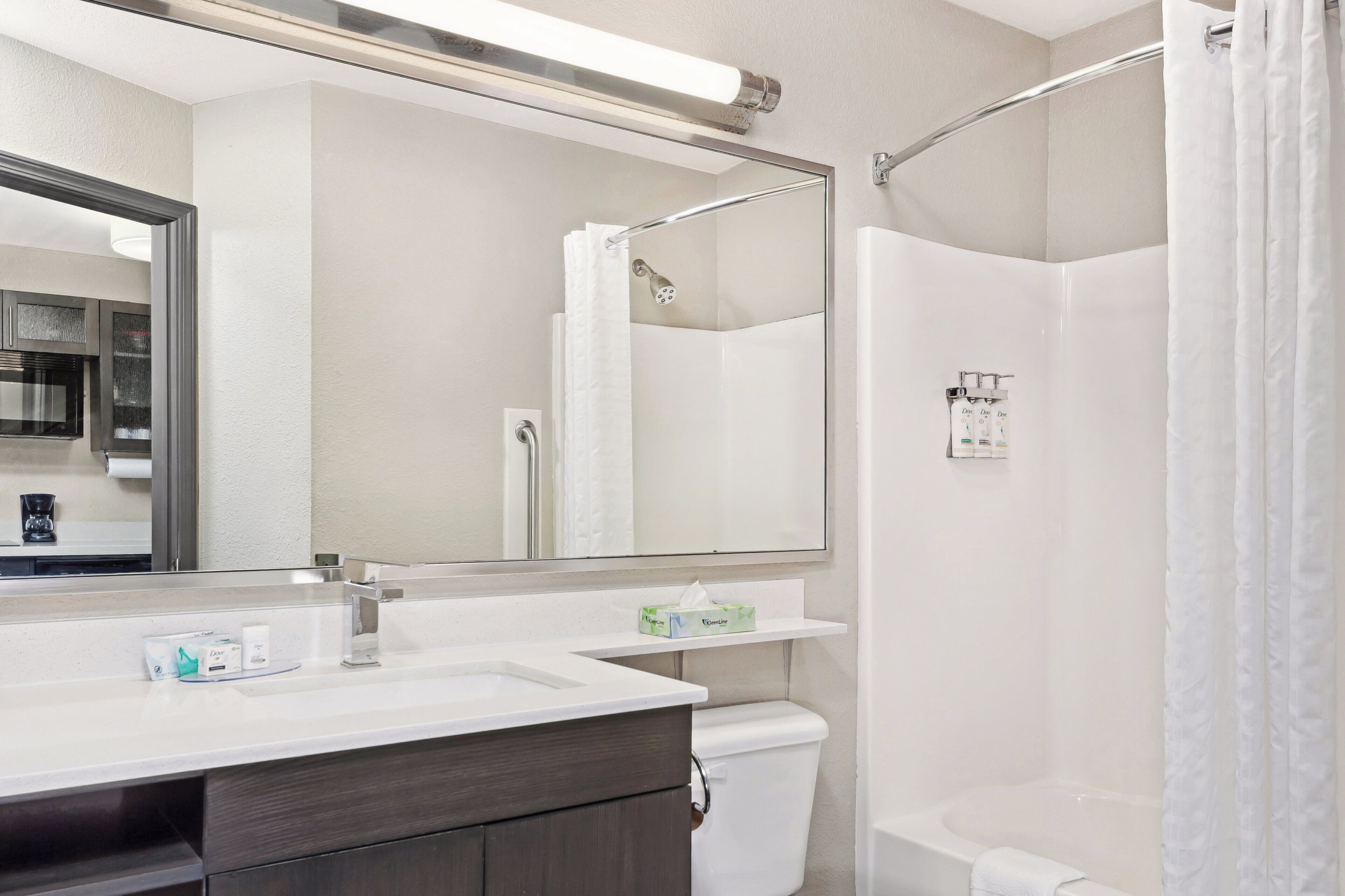 A bathroom with a white sink, mirror, and shower.