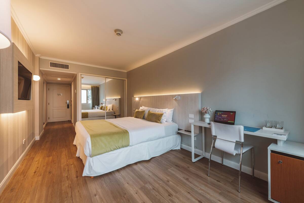 Une chambre d’hôtel équipée d’un lit, d’un bureau, d’une chaise et d’un petit placard.