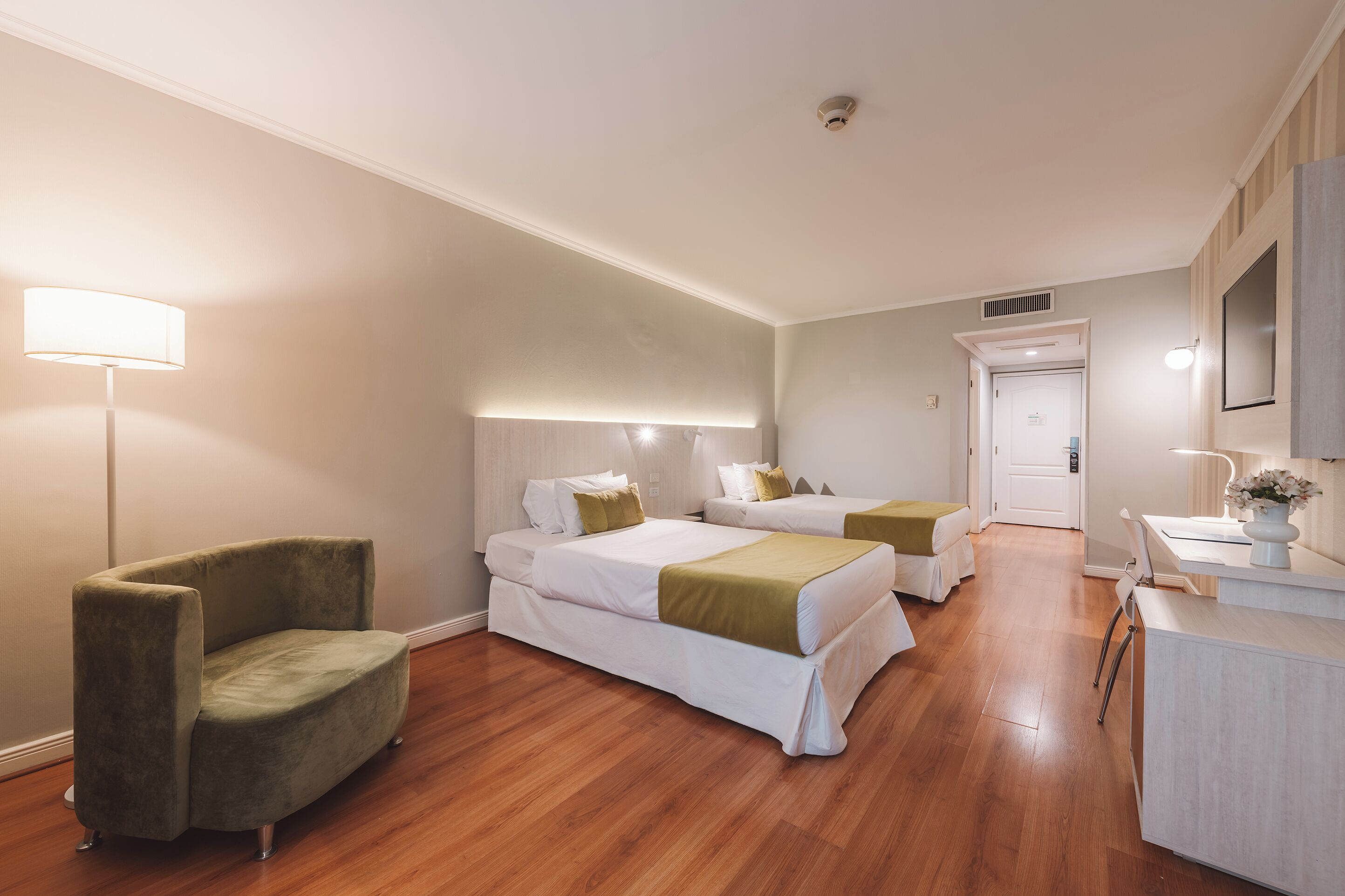 Habitación de hotel con dos camas, una silla, un escritorio y un espejo.