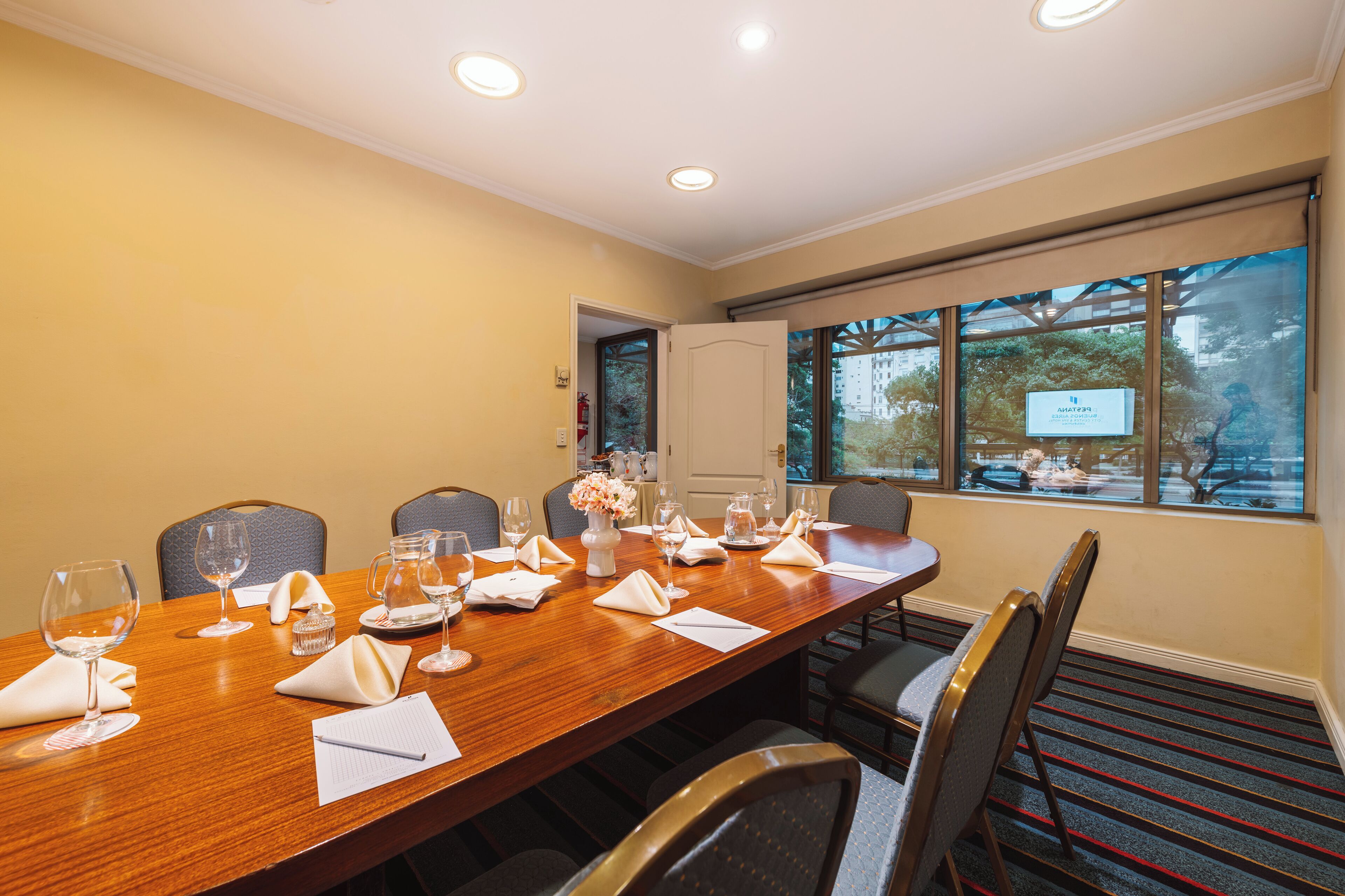 A conference room with a long table, chairs, and a projector screen.