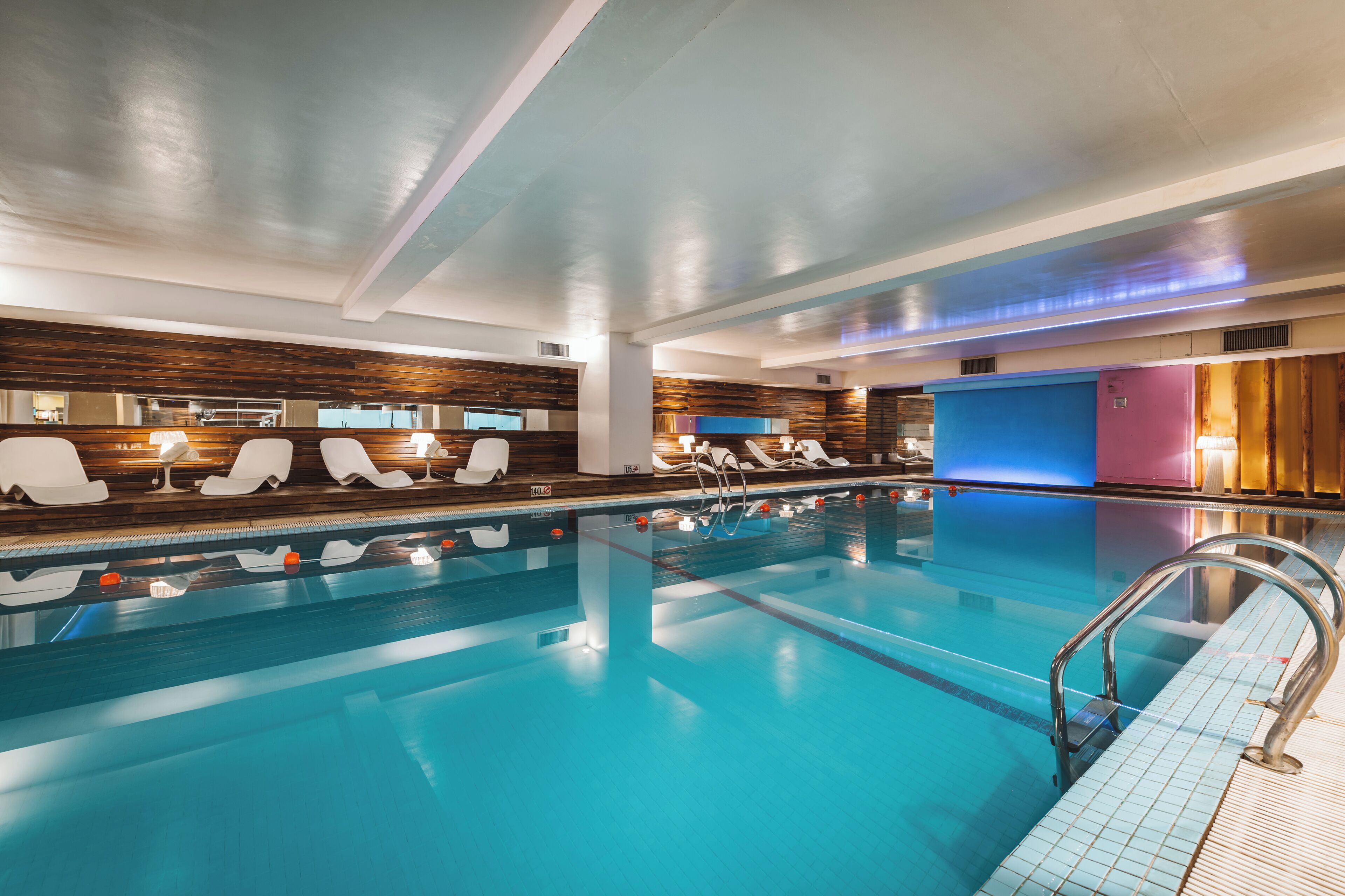 Una piscina con sillones de descanso y vestuarios.