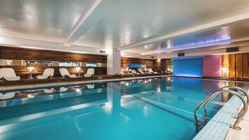 Una piscina con sillones de descanso y vestuarios.