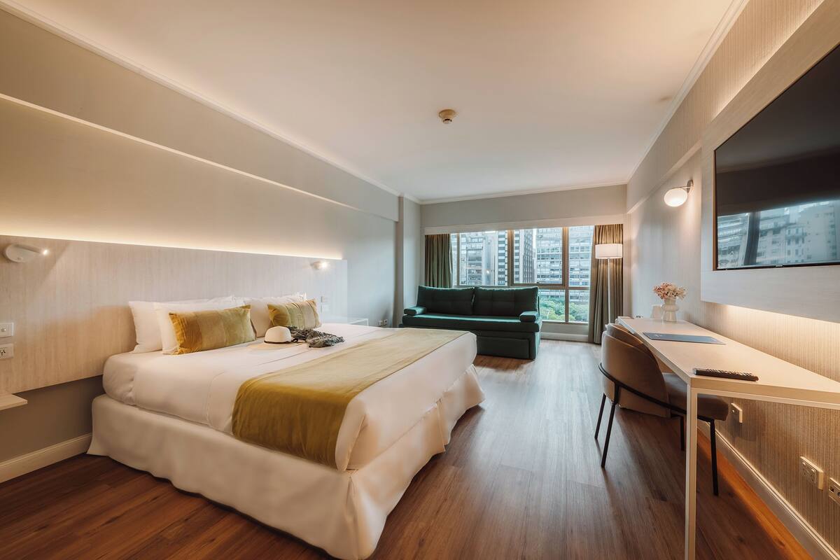 Une chambre d’hôtel moderne, dotée d’un grand lit, d’un bureau et offrant une vue sur la ville.