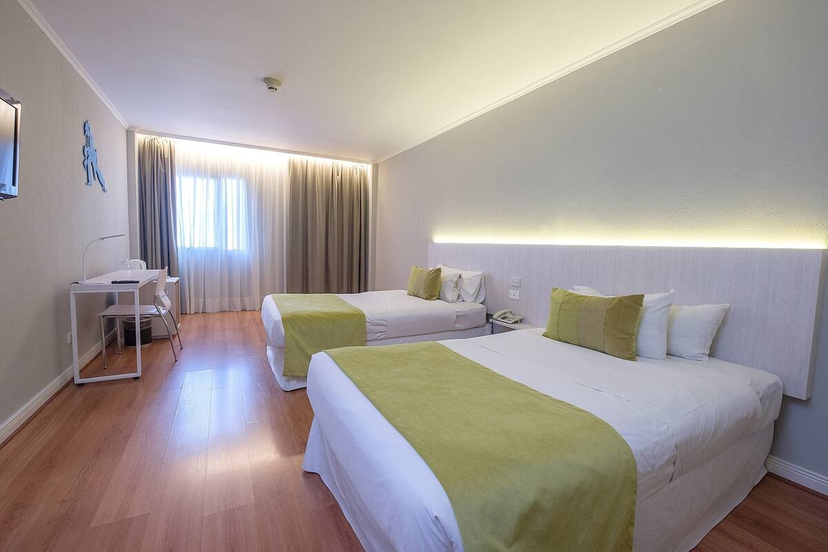 Une chambre d’hôtel avec deux lits, un bureau et une chaise.