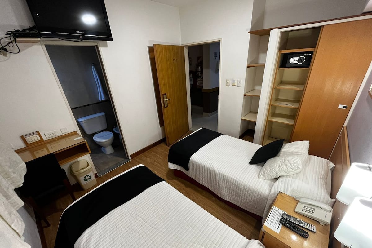 A hotel room with two beds, a TV, a bathroom, and a closet.