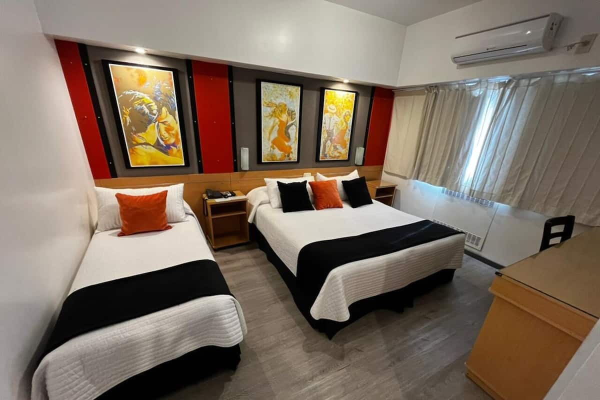 A hotel room with two beds, a wooden headboard, a small desk, and a minibar.