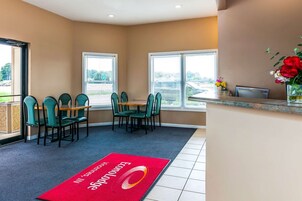 Habitación de hotel con comedor, ventanas amplias y alfombra roja con un logotipo.