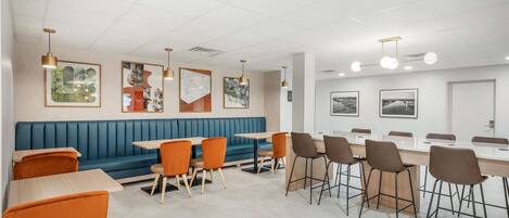 A modern dining area with a blue booth, orange chairs, and a long table.