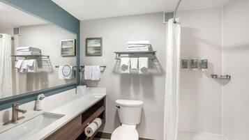 Un bagno moderno con lavandino, WC e doccia. Asciugamani e articoli da toilette sugli scaffali.