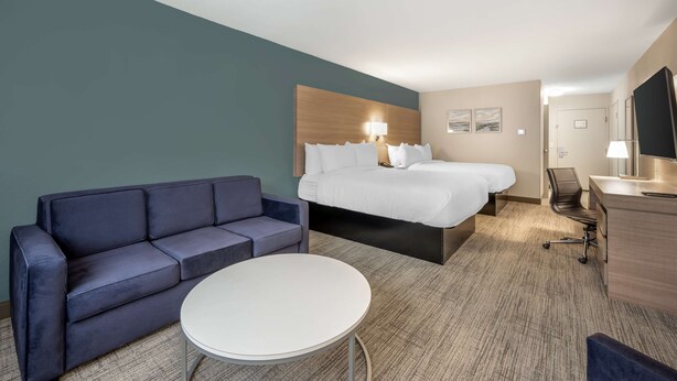 A hotel room with a bed, a sofa, a desk, and a chair. - Best Western River Cities (Russell)