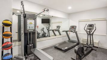 A gym with exercise equipment, a bench, and a treadmill.