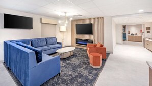 A modern living room with a sectional sofa, a coffee table, and a flat-screen TV. - Best Western River Cities (Russell)