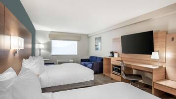 A hotel room with two beds, a desk, a chair, a TV, and a window.