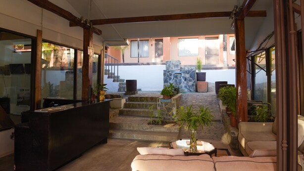 A reception area with a counter, seating, and a view of the outside. - Coco Beach Hotel (Sardinal)