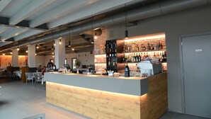 A modern bar area with a wooden counter, a brick wall, and a variety of bottles and glasses. - Albergo Roma, BW Signature Collection (Castelfranco Veneto)