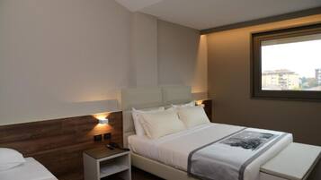 Una habitación de hotel moderna con una cama grande, una mesita de noche y un pequeño escritorio.