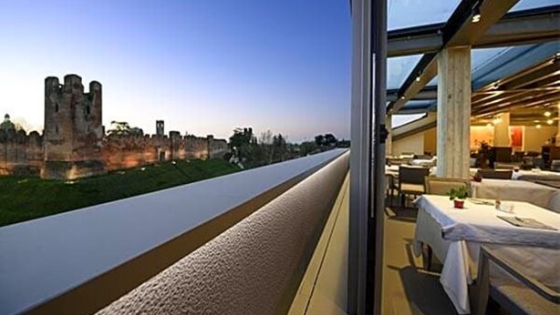 A modern hotel room with a large window overlooking a castle and a paved path. - Albergo Roma, BW Signature Collection (Castelfranco Veneto)