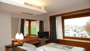 A hotel room with a bed, a desk with a computer, a TV, and a window with a city view. - Albergo Roma, BW Signature Collection (Castelfranco Veneto)