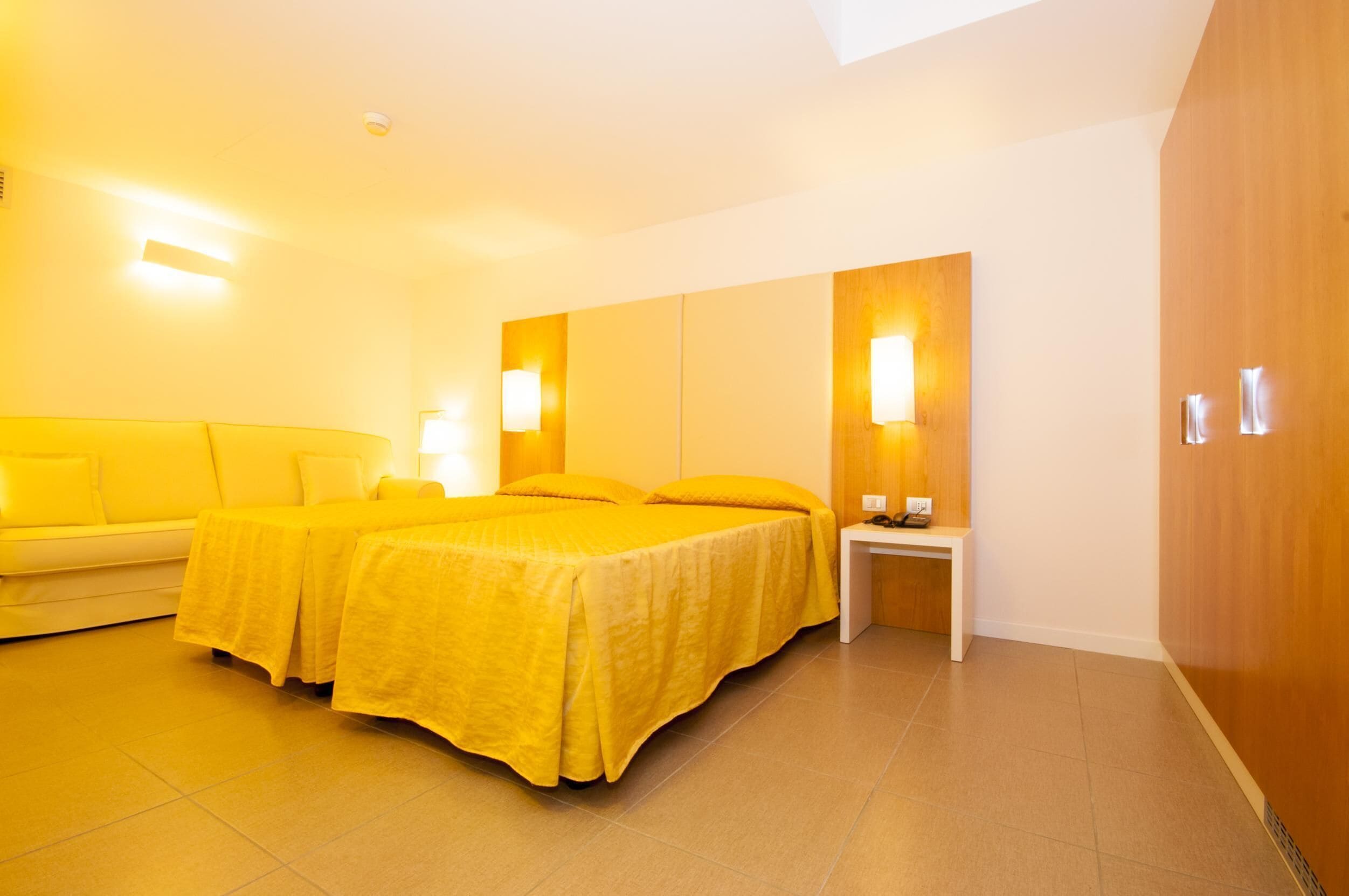Una habitación de hotel con una cama grande, una mesita de noche, una lámpara y un sofá.