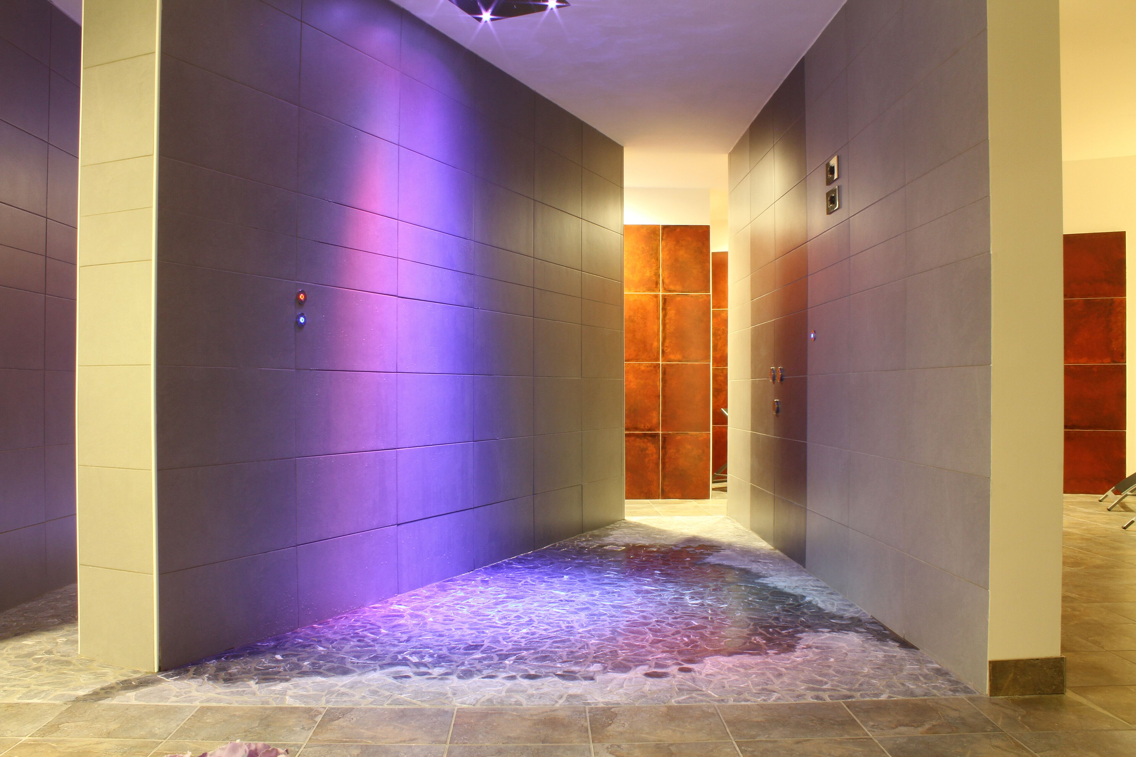 A hallway with a water feature on the floor, a wooden door at the end, and a light fixture on the ceiling.