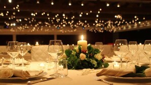Una mesa dispuesta para una cena formal, con velas, copas y un centro de mesa de flores.