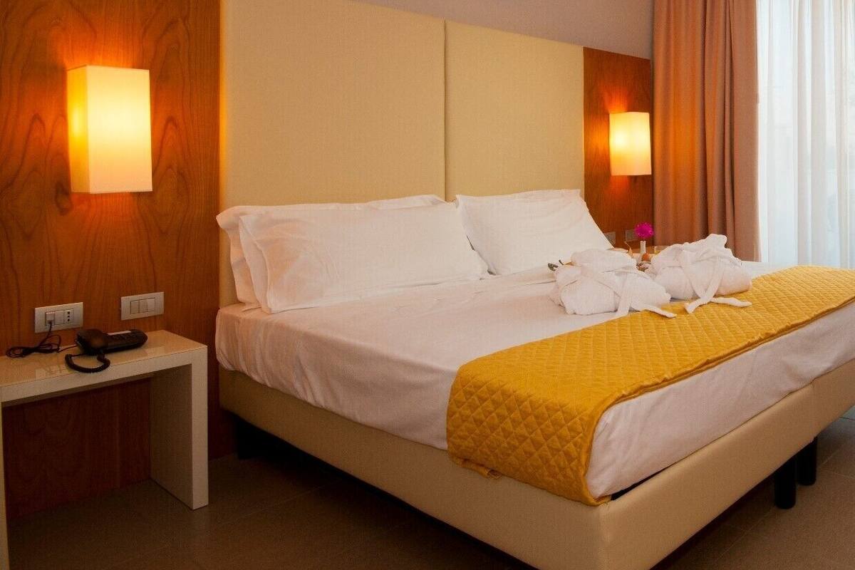 Een hotelkamer met een bed, nachtkastjes en wandlampen.