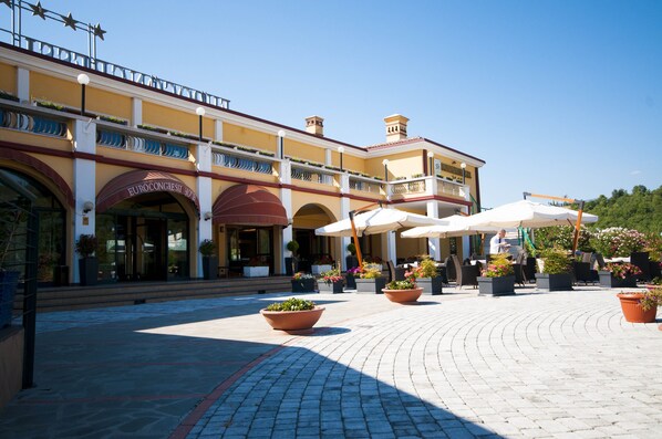 A hotel with a courtyard, outdoor seating, and a clear blue sky. - Hotel Eurocongressi (Cavaion Veronese)