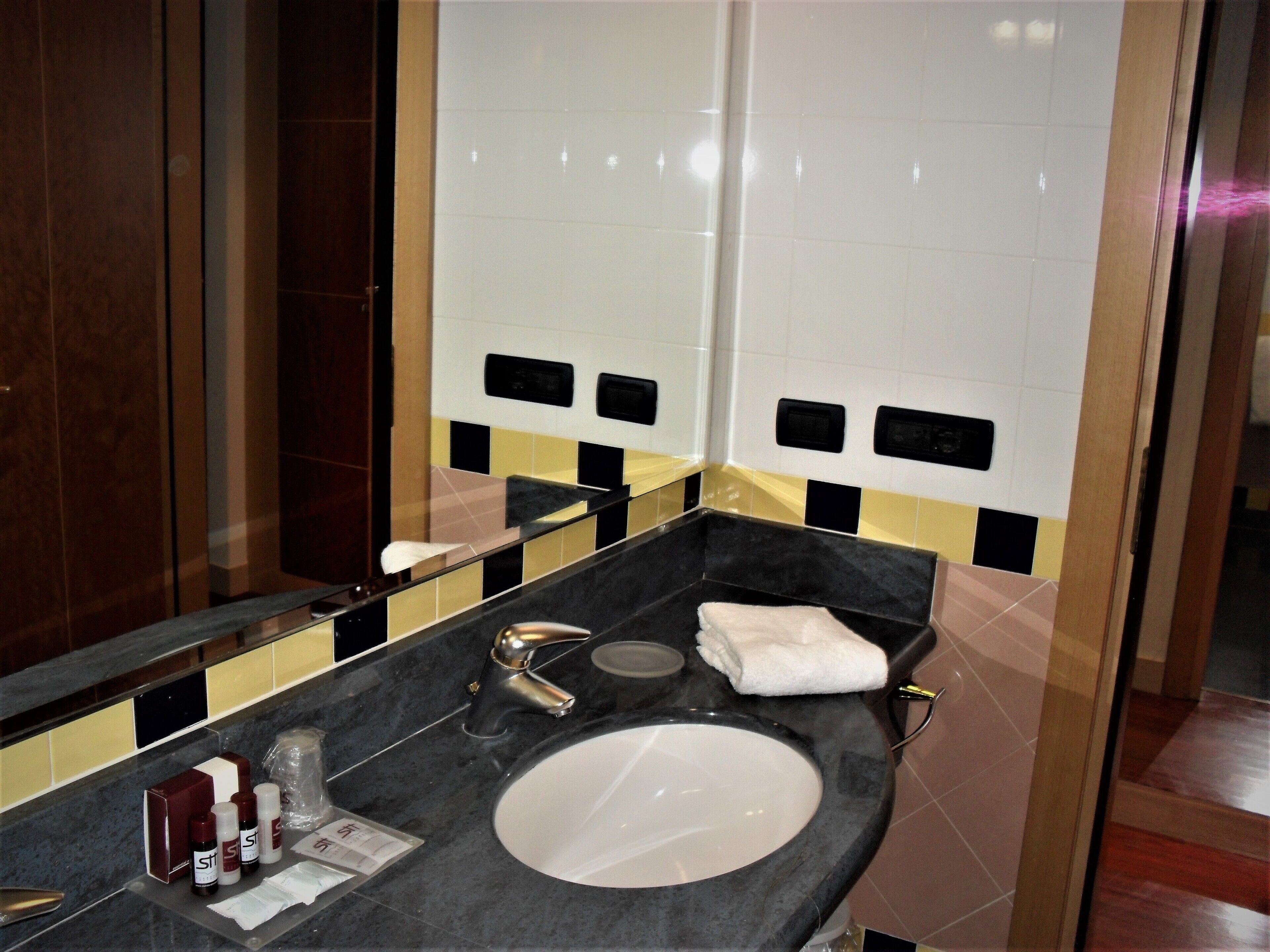 A bathroom with a sink, mirror, and toiletries.