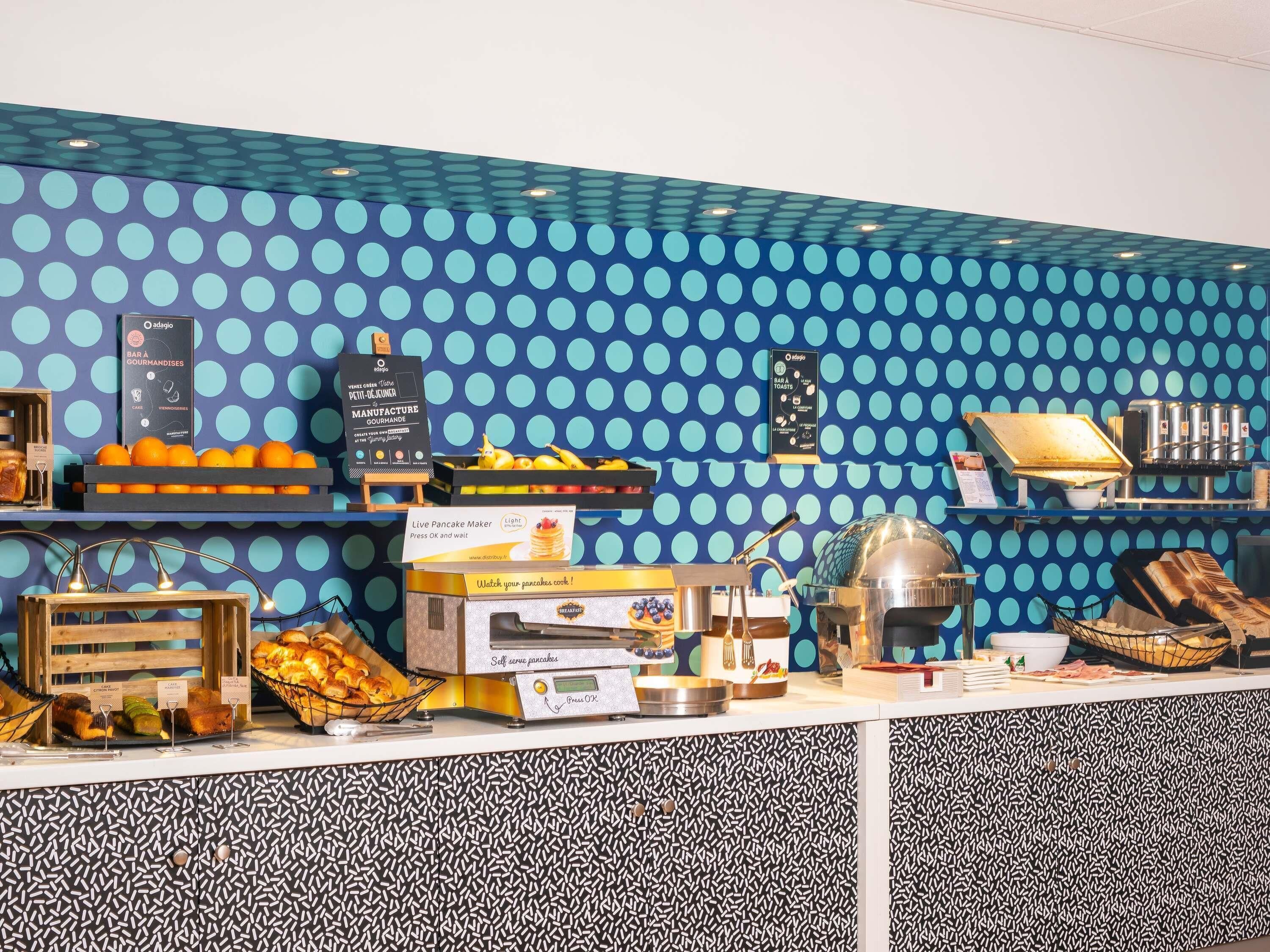 A breakfast bar with a polka dot wall, a live pancake maker, and a self-serve pancake station.