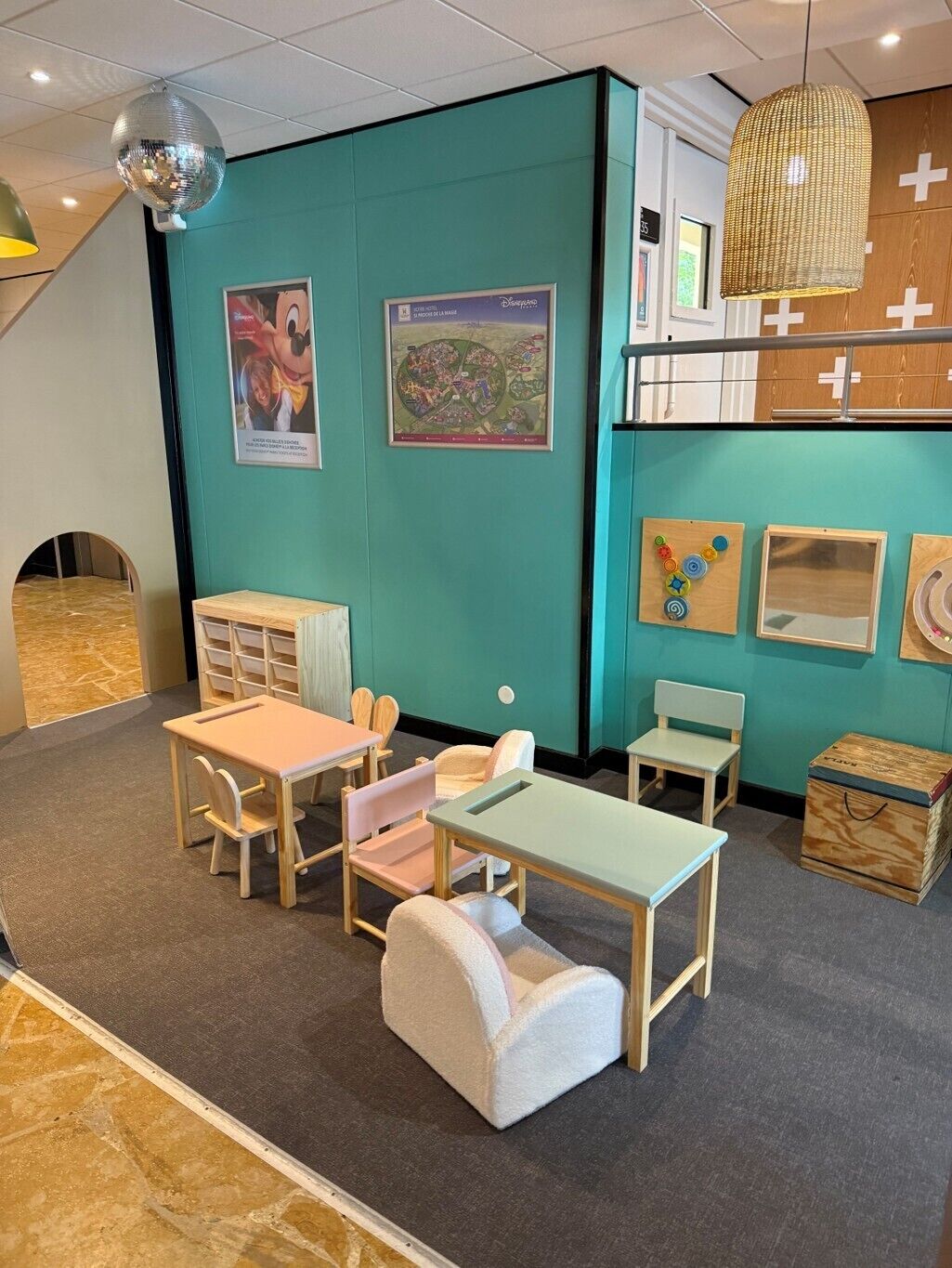 A children's playroom with teal walls, wooden furniture, and educational posters.