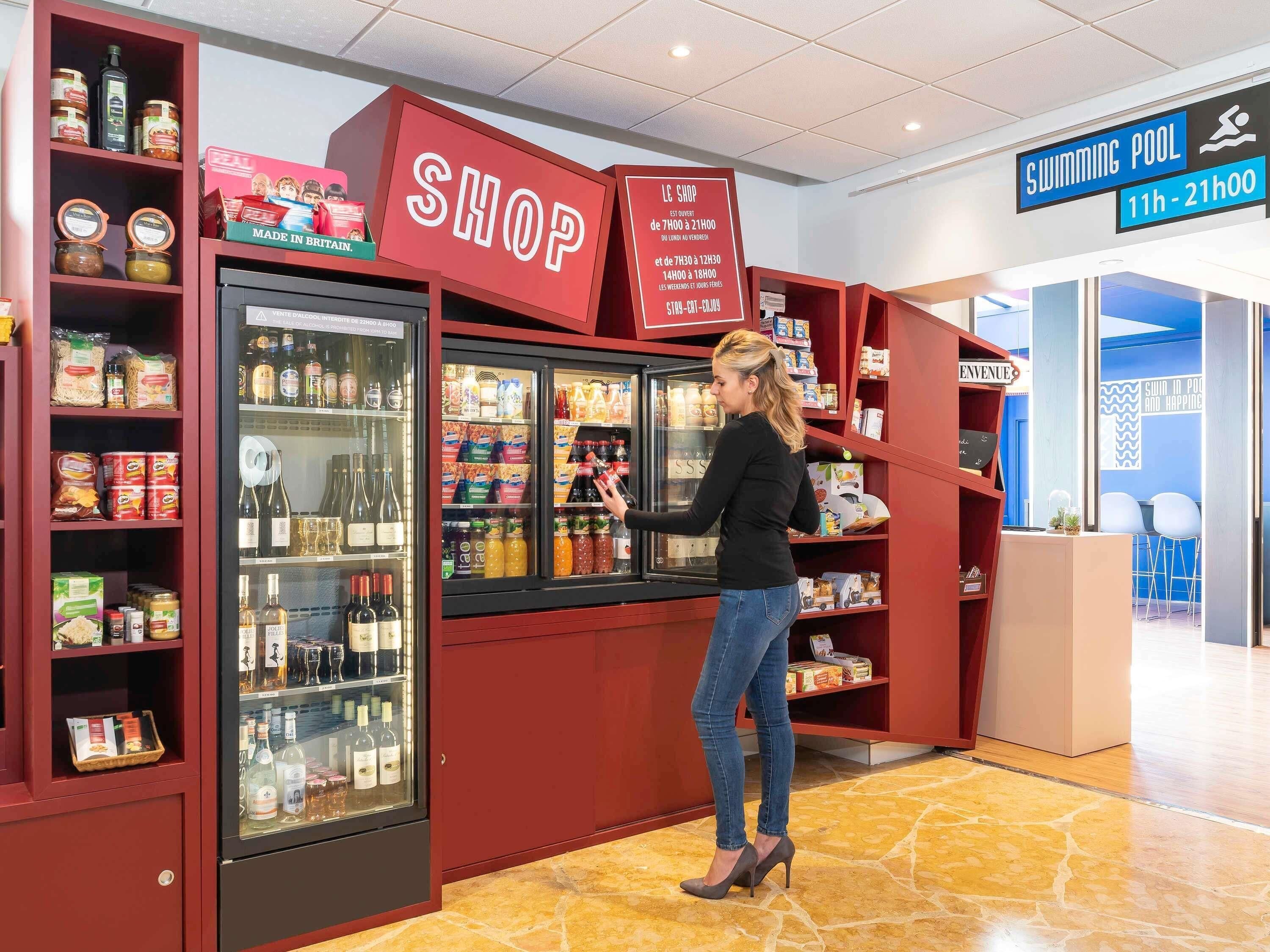 Een persoon in een winkel met een koelvitrine en planken vol met diverse producten.