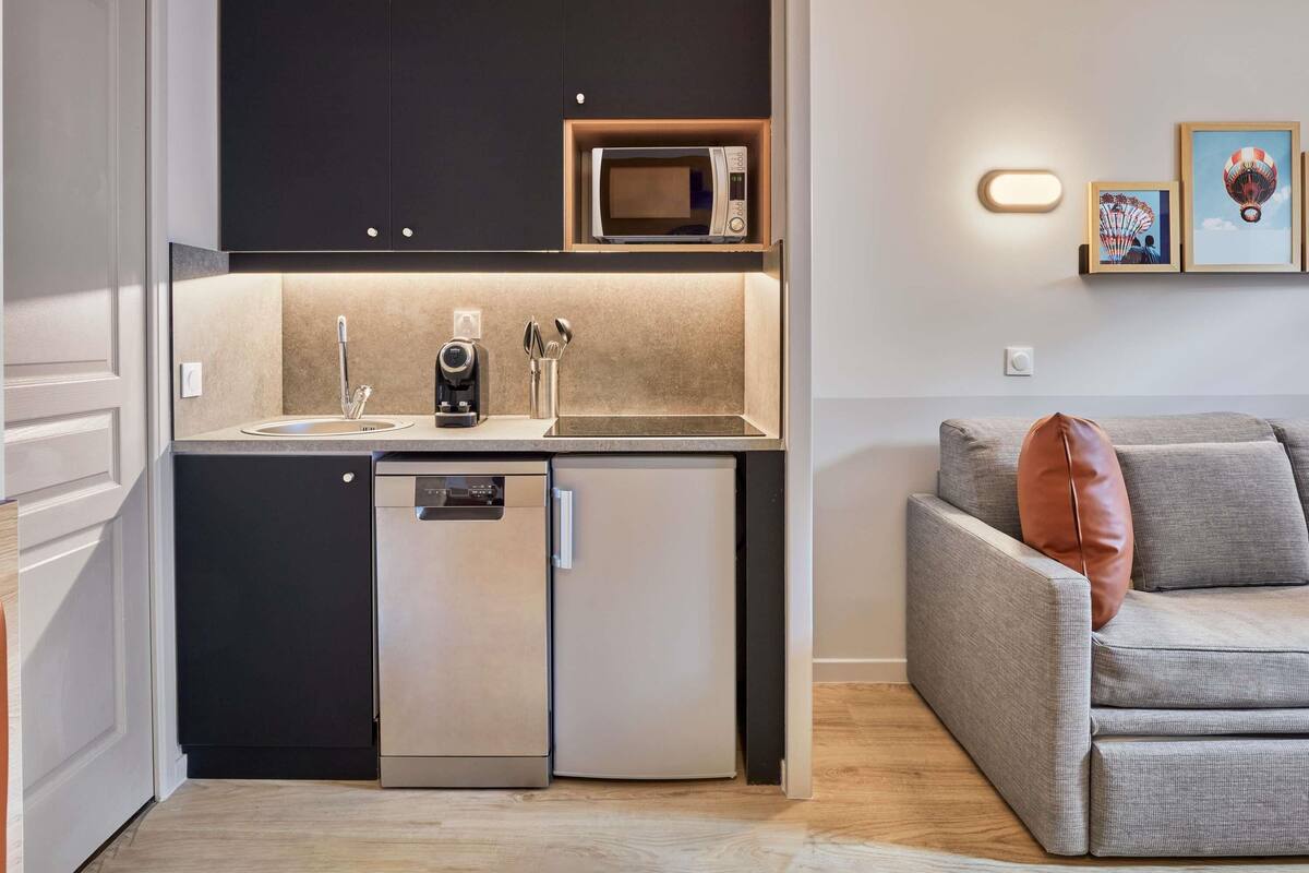 A compact kitchen with a dishwasher, a microwave, and a coffee machine.