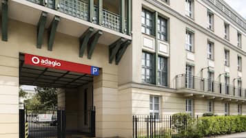 Ein Adagio Apartmenthaus mit Parkeingang, befahrbarer Allee mit Tor und Balkon mit Metallgeländer.