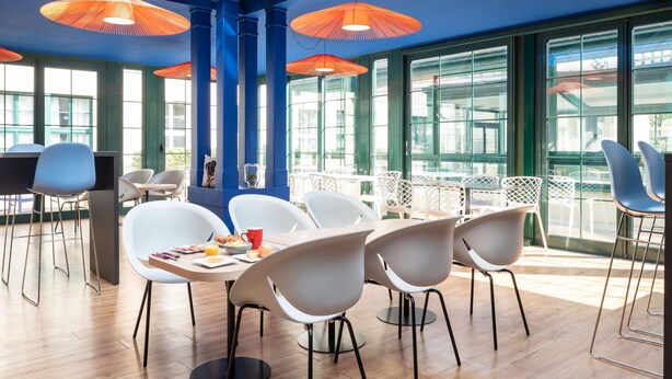 A modern dining area with high ceilings, large windows, and orange hanging lamps. - Aparthotel Adagio Val d'Europe près de Disneyland Paris (Serris)