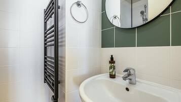Une salle de bain avec un lavabo blanc, un miroir, un porte-serviette et un étendoir à serviettes.