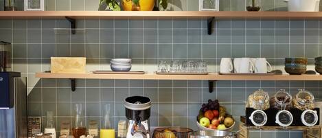 Una cocina con estantes que sostienen cristalería, una cafetera y un frutero.