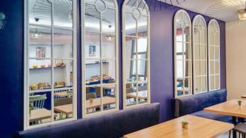 Een restaurant met grote gewelfde ramen, houten tafels en zachte zitplaatsen.