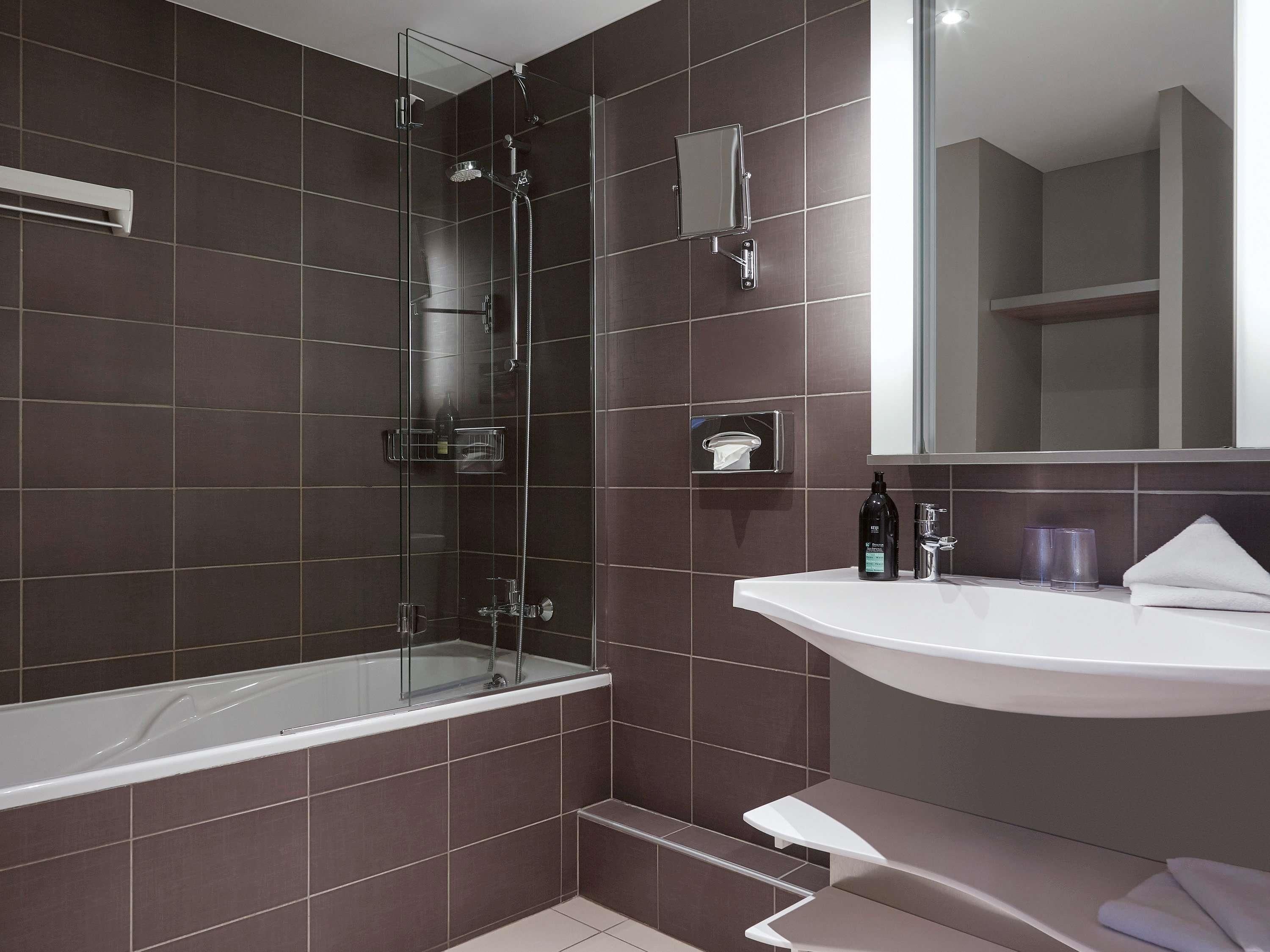 A modern bathroom with a glass-enclosed shower, a white sink, and a mirror above the sink.